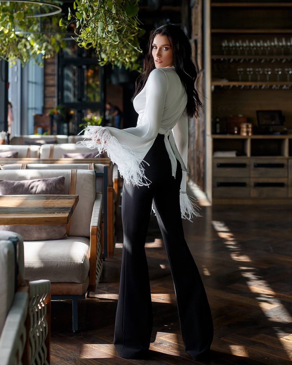 Woman in a white blouse and black pants standing in a restaurant setting