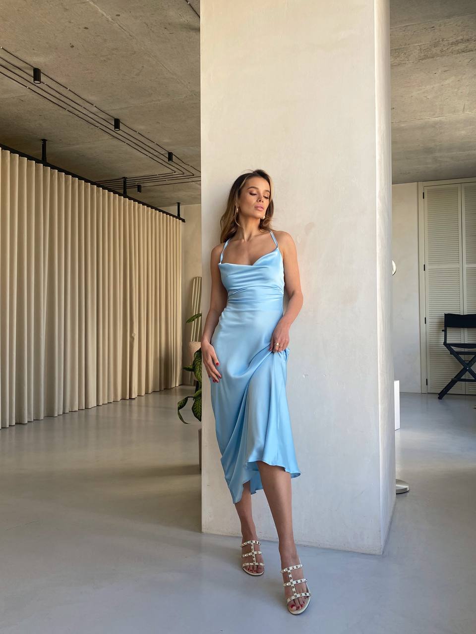 Woman in a light blue dress standing in a modern indoor setting.