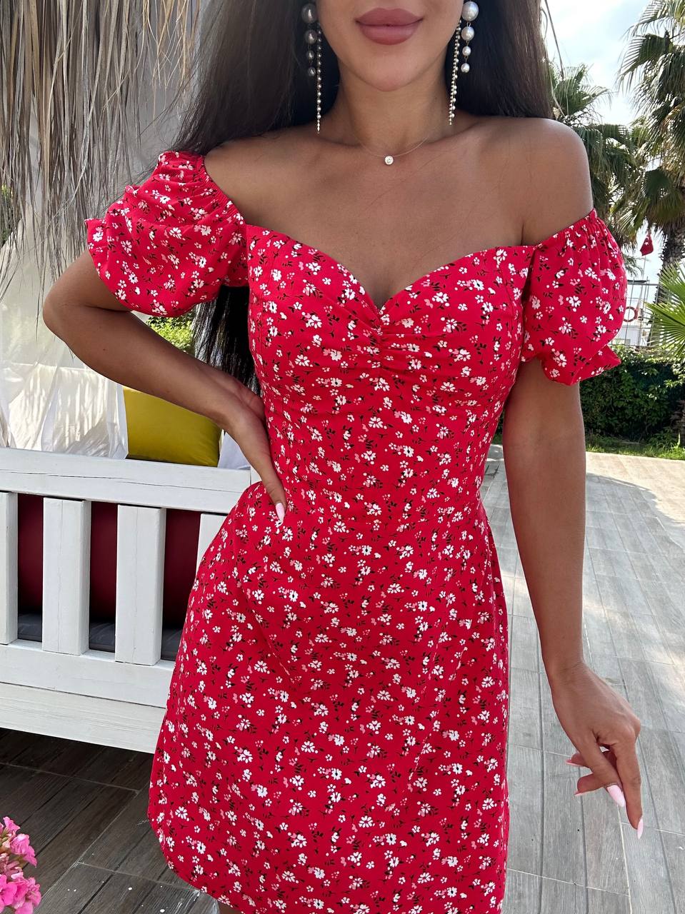 Woman wearing a red floral off-shoulder dress outdoors.