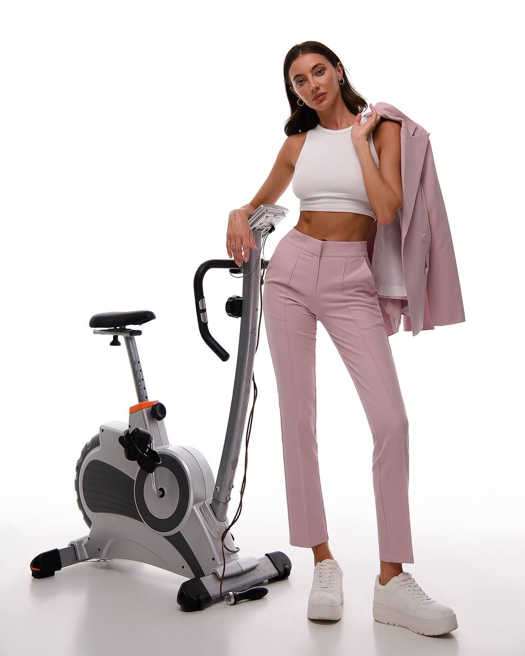 Woman standing next to a stationary bike on a white background