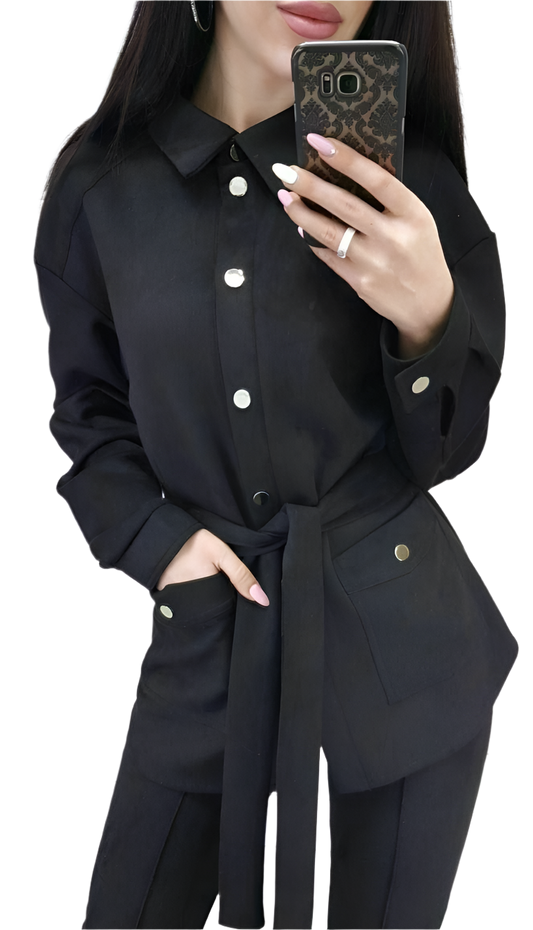 Person wearing a black outfit with white buttons, holding a phone.