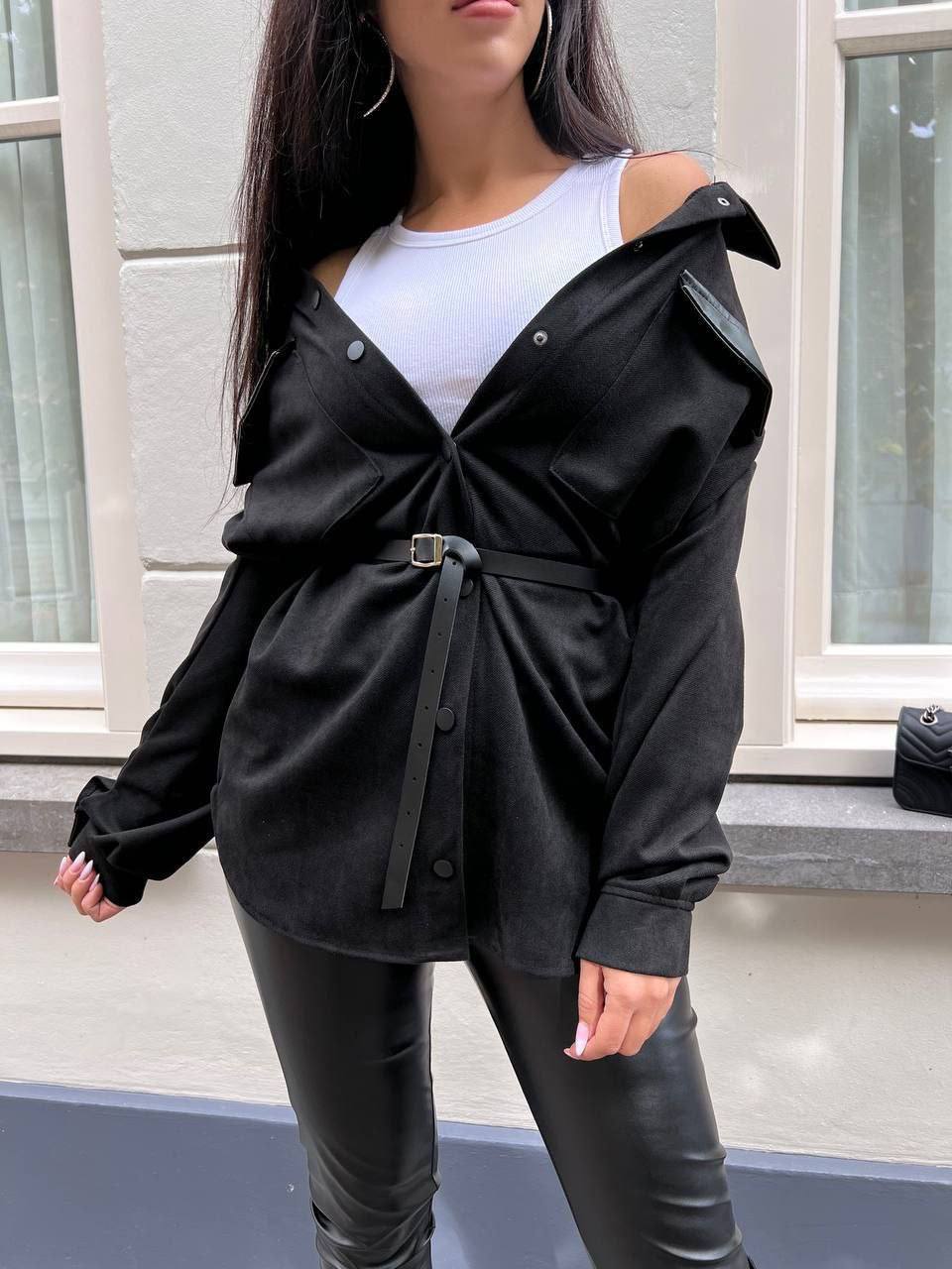 Person wearing a black jacket with a white top and black pants in an indoor setting.