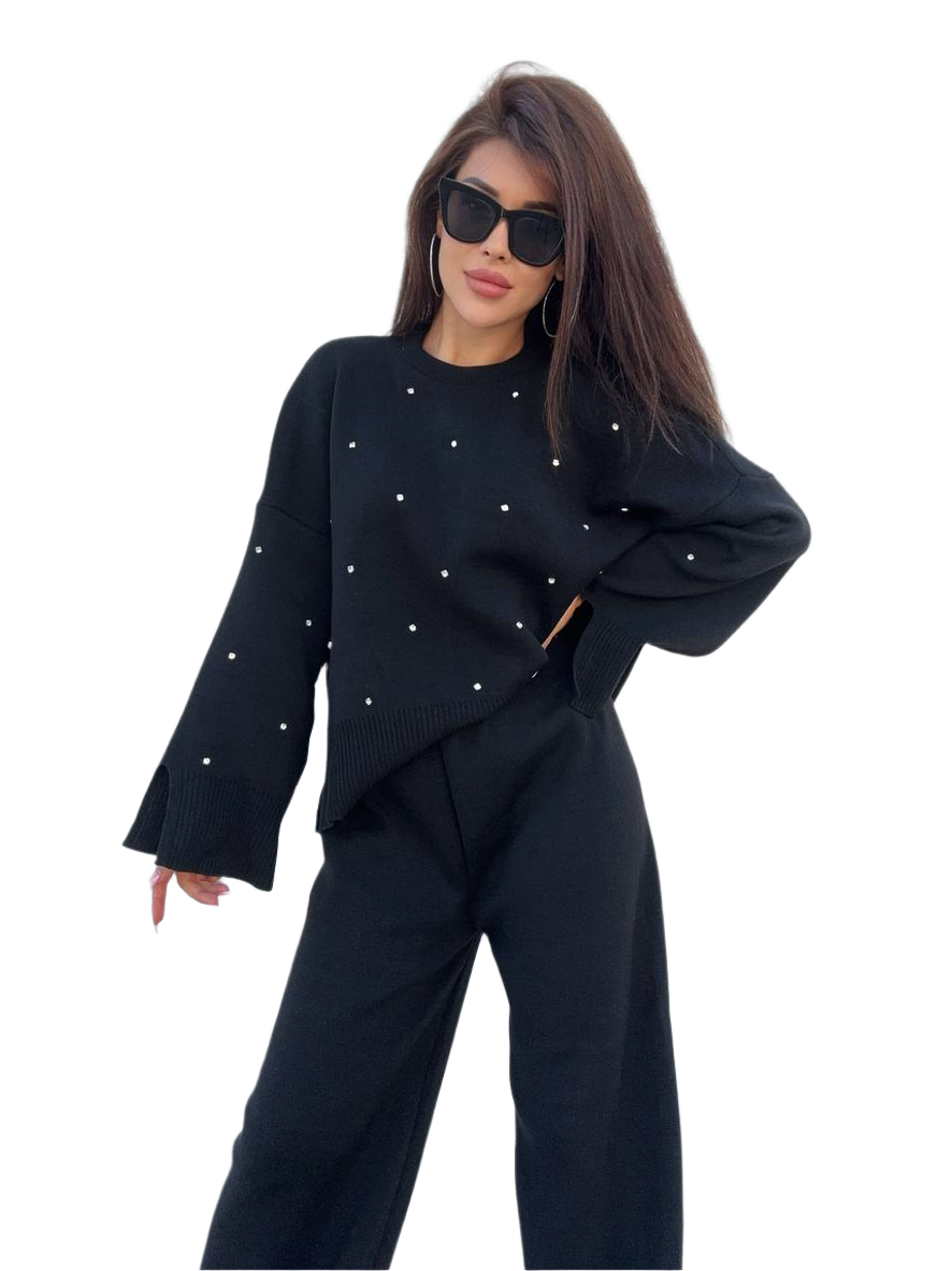 Woman wearing a black outfit with white embellishments on a white background