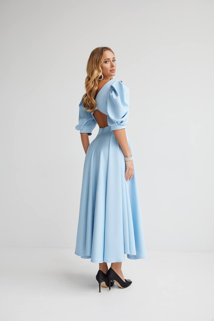 Woman wearing a light blue dress with cut-out shoulders on a white background