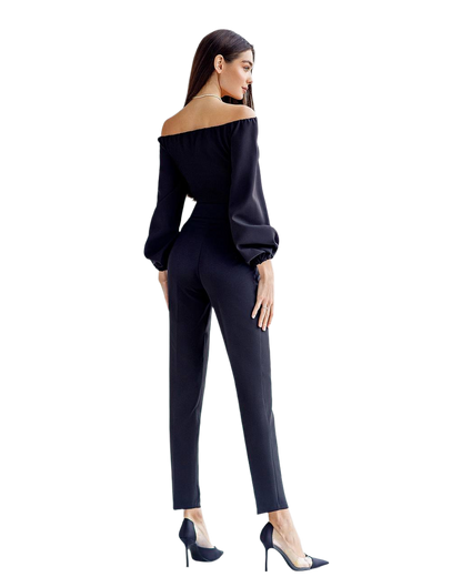 Woman wearing a black off-shoulder top and pants on a white background