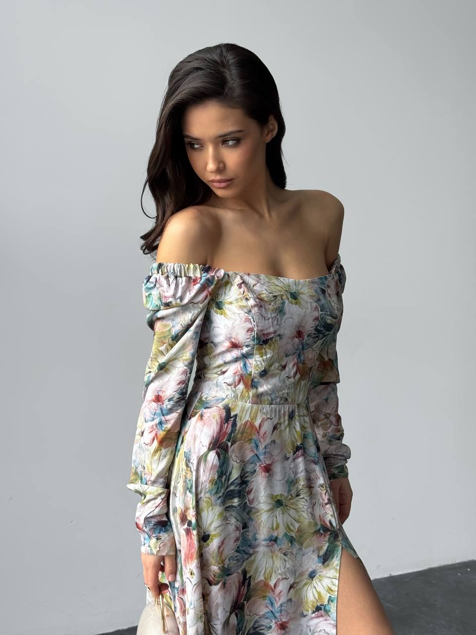 Woman wearing a floral off-shoulder dress against a plain background
