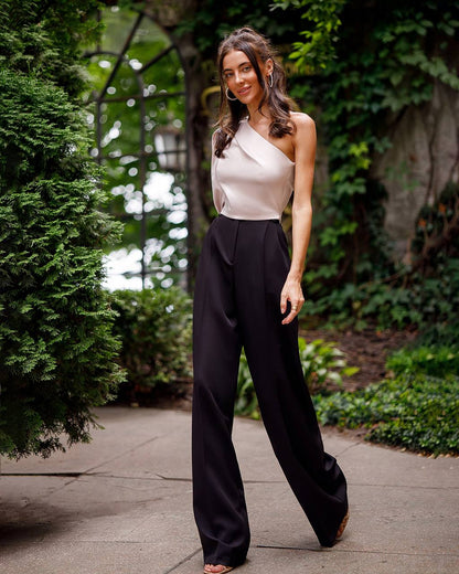 Woman in a white top and black pants walking outdoors with greenery in the background