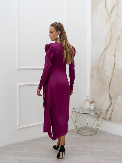 Woman in a purple dress standing in a room with a marble wall.