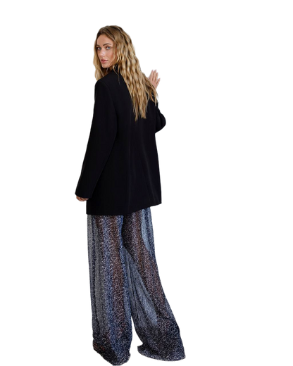 Person wearing a black coat and patterned pants on a white background