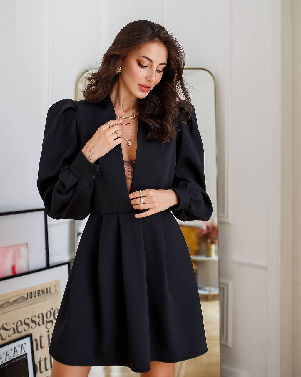 Woman wearing a black dress with puffed sleeves in an indoor setting.