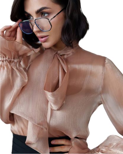 Woman wearing a beige blouse with a tie detail and sunglasses on a white background