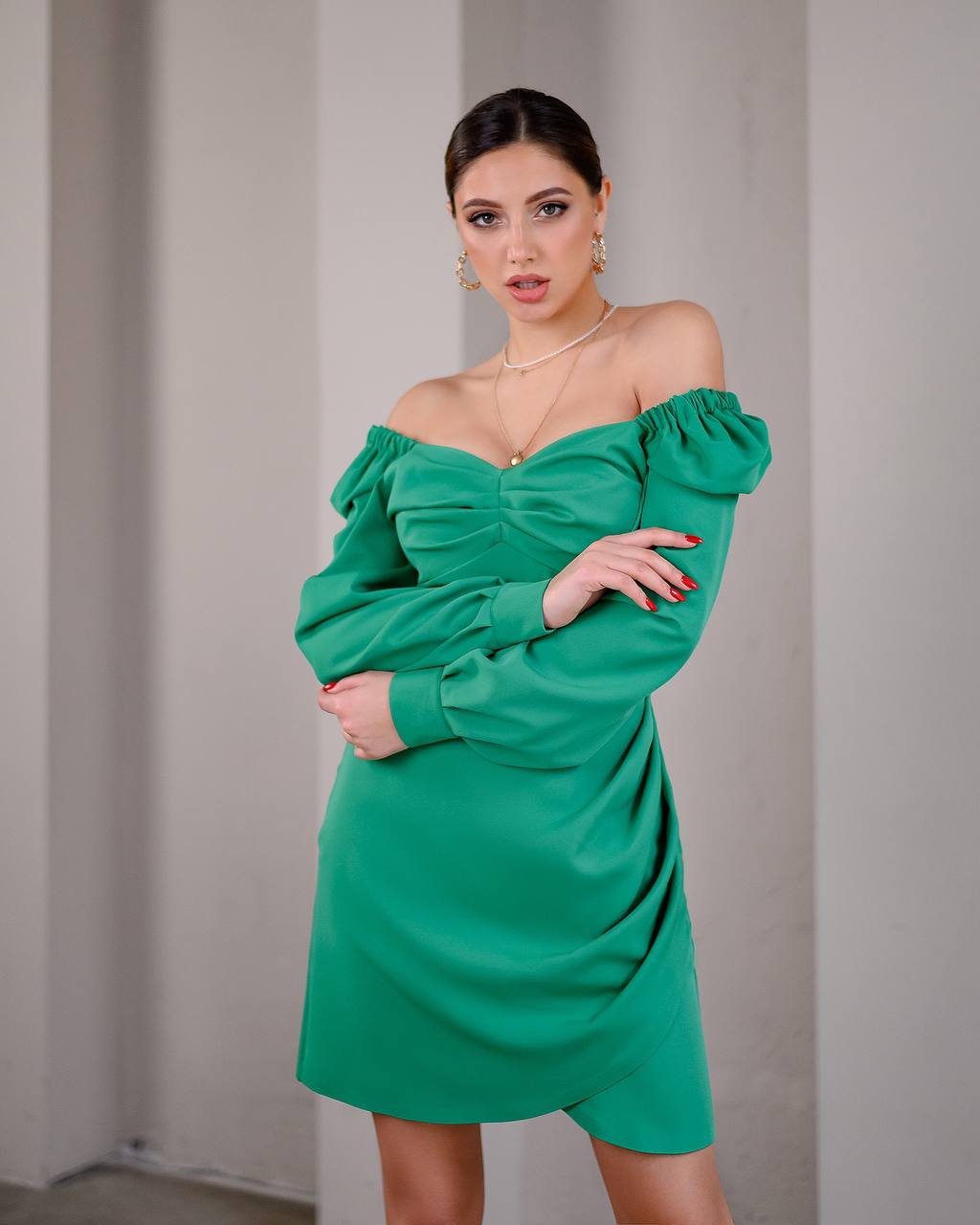 Woman wearing a green off-shoulder dress against a plain background