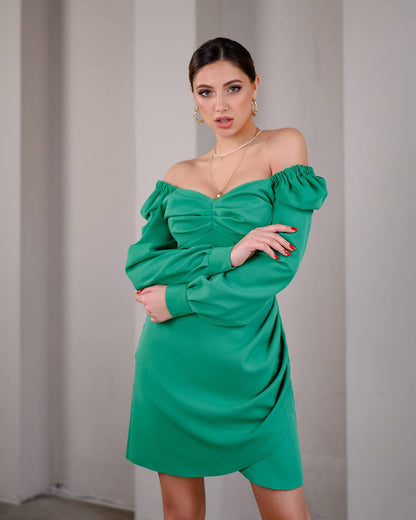 Woman wearing a green off-shoulder dress against a plain background