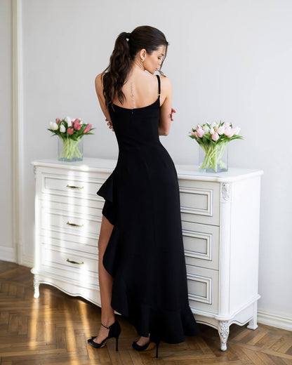 Woman in a black dress standing in front of a white dresser with floral arrangements.