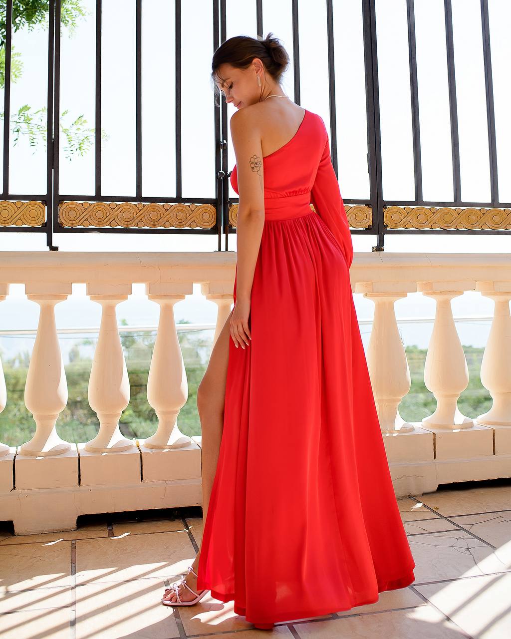 Woman in a red dress standing on a balcony with a scenic background