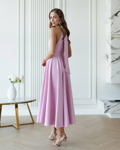 Woman in a pink dress standing in a modern room with white walls and marble accents.
