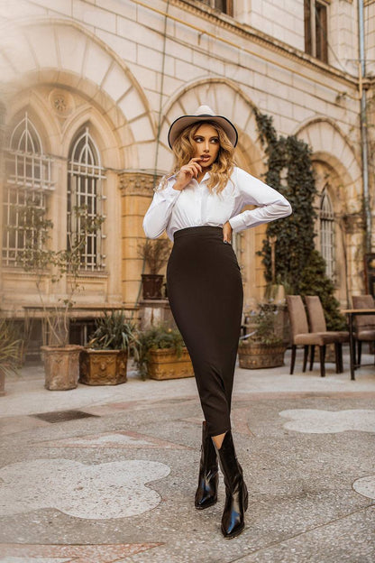 Woman in a stylish outfit standing in an outdoor setting with architectural elements.