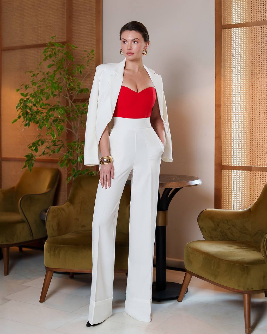 Woman in a white suit with a red top in an indoor setting
