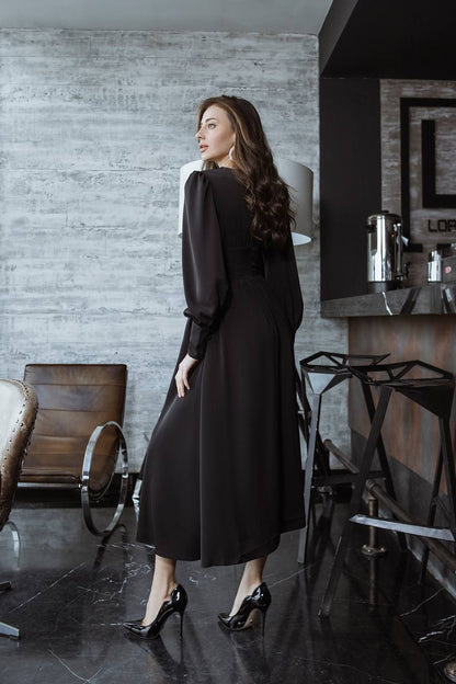 Woman in a black dress standing in a modern interior setting