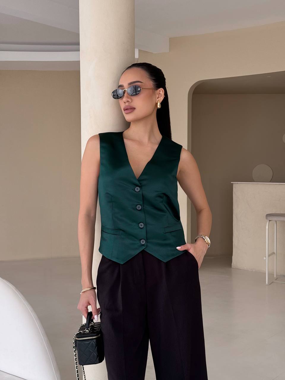 Woman wearing a green vest and black pants in an indoor setting