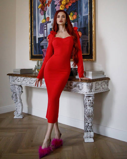 Woman in a red dress standing on a decorative table with a colorful painting in the background