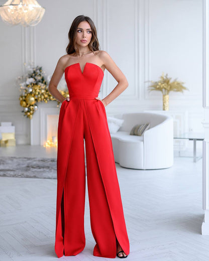 Woman wearing a red strapless jumpsuit in a stylish room with decor elements.