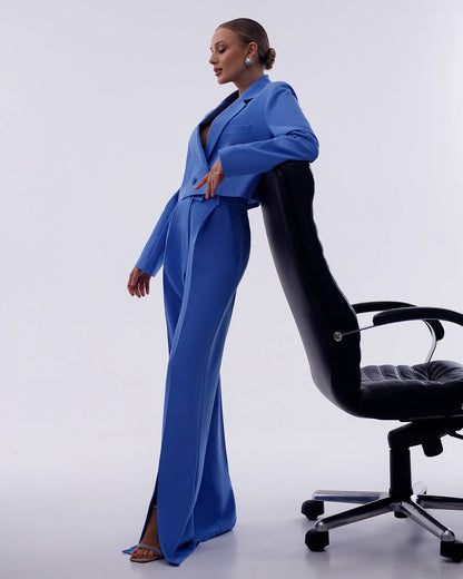 Person wearing a blue outfit sitting on a black office chair against a white background