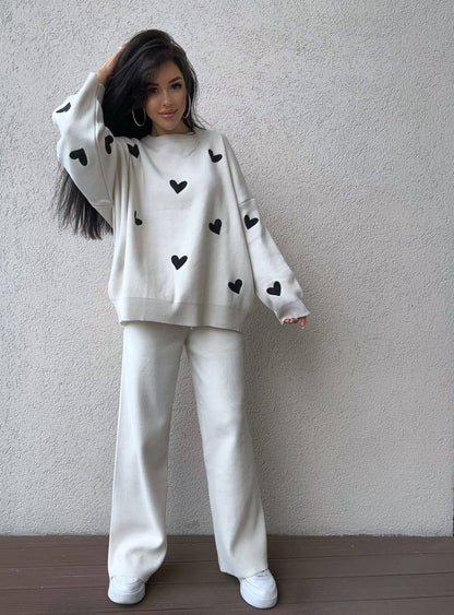 Person wearing a white outfit with black heart patterns against a plain background