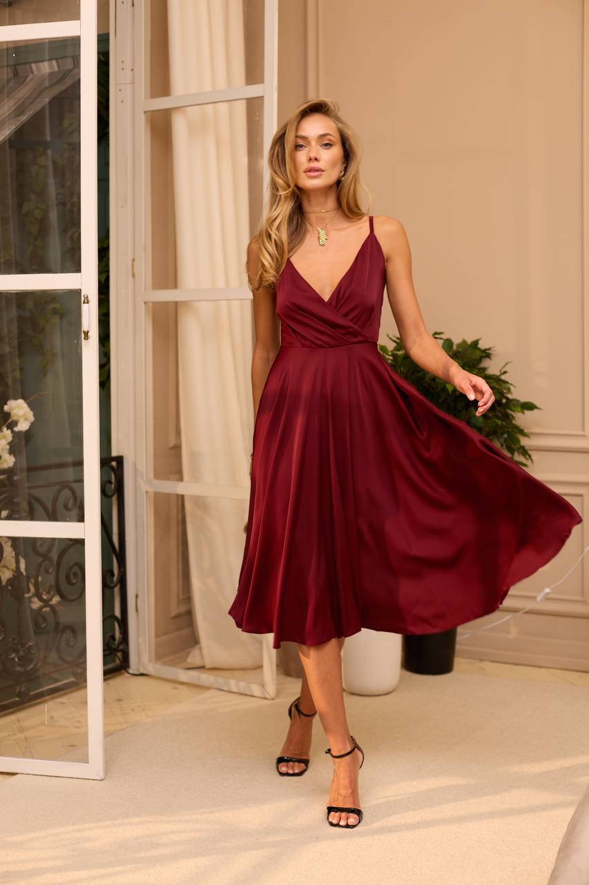 Woman in a burgundy dress standing in a room with decorative elements.