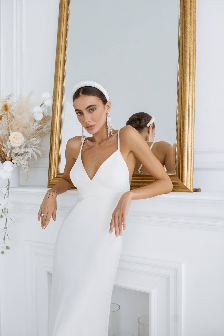 Woman in a white wedding dress standing in front of a mirror.