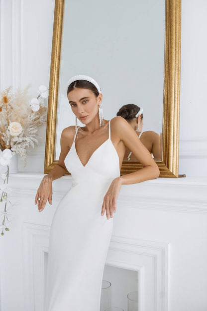 Woman in a white wedding dress standing in front of a mirror.