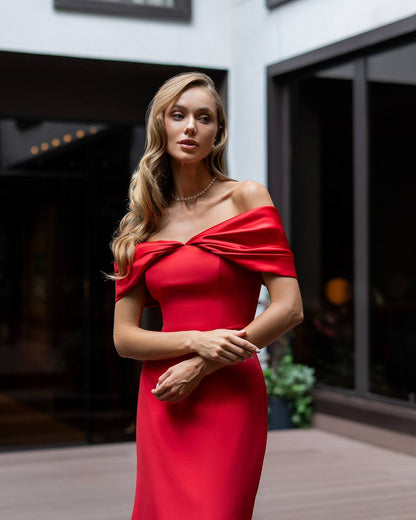 Woman in a red off-shoulder dress standing outdoors.