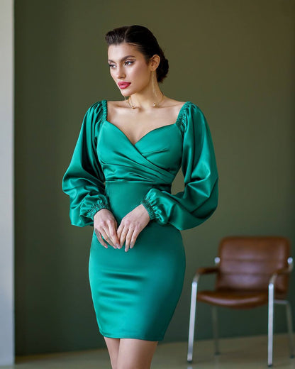 Woman wearing a green dress with puffed sleeves against a plain background