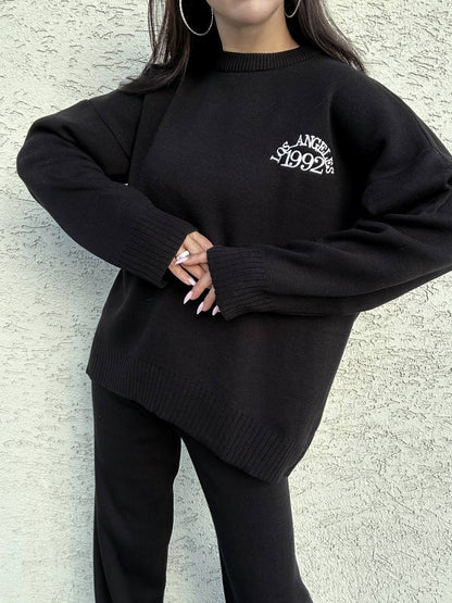 Person wearing a black sweater with 'Los Angeles 1992' text against a light gray background