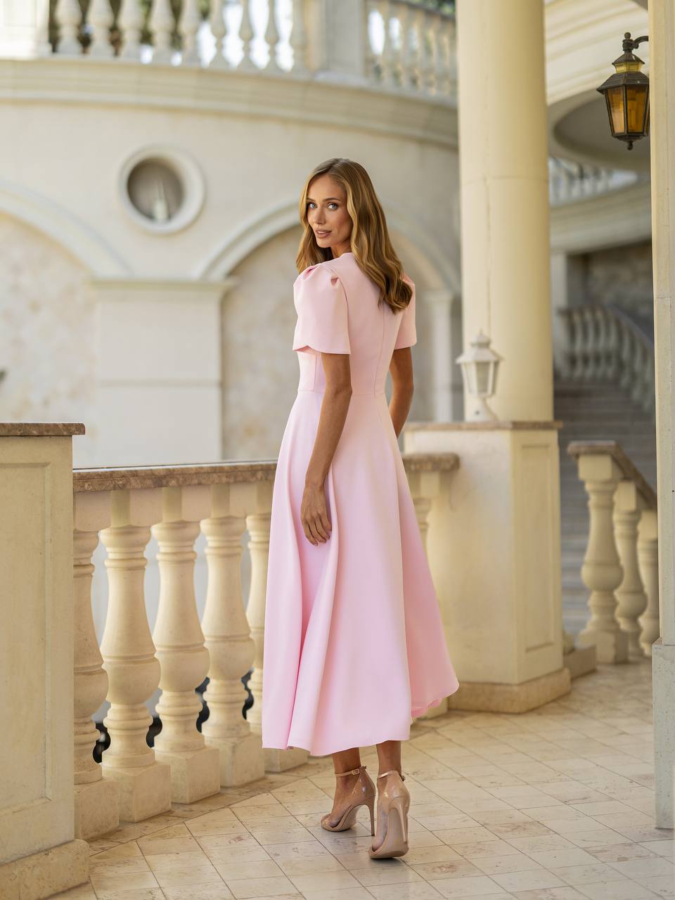Woman in a pink dress standing in an elegant interior setting