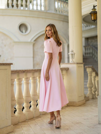 Woman in a pink dress standing in an elegant interior setting