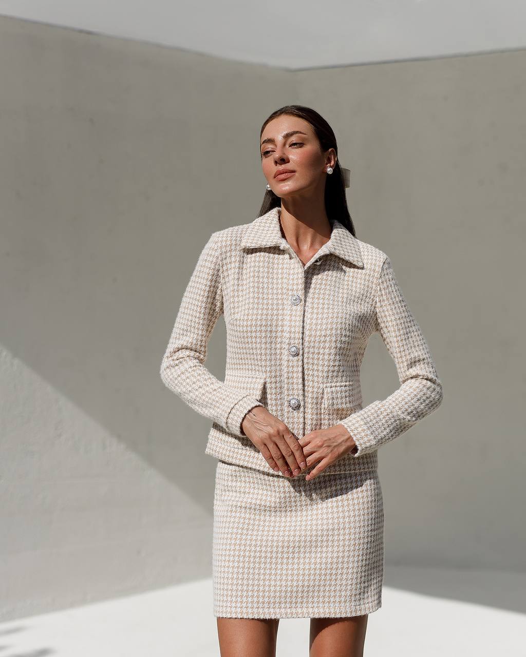 Woman wearing a checkered suit standing against a plain background