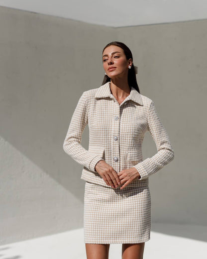 Woman wearing a checkered suit standing against a plain background