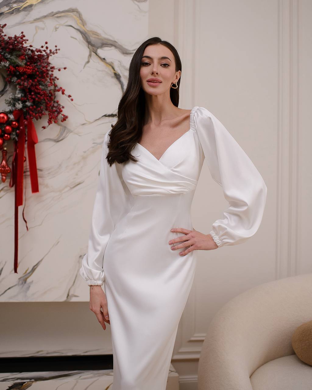 Woman in a white dress standing in a room with decorative elements.