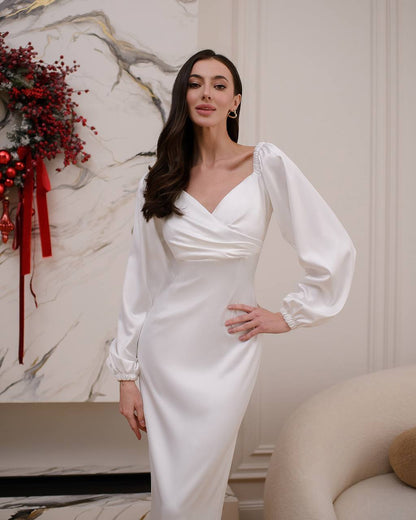 Woman in a white dress standing in a room with decorative elements.