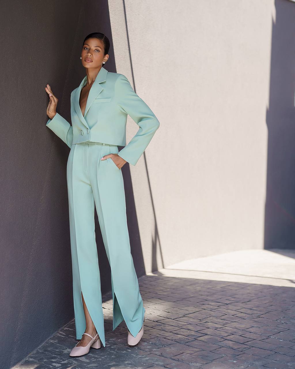 Woman in a light blue suit standing against a neutral background