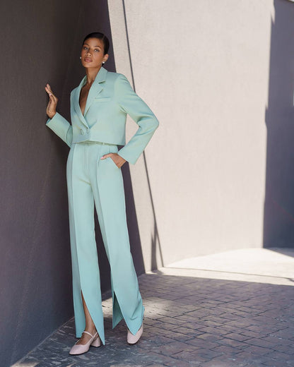 Woman in a light blue suit standing against a neutral background