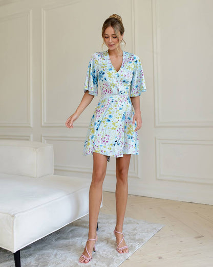 Woman wearing a floral dress in a room with white walls and a white couch.