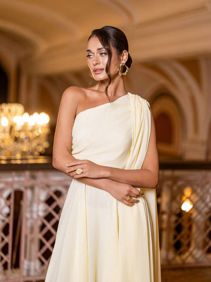 Woman in a light yellow saree standing in an elegant indoor setting.
