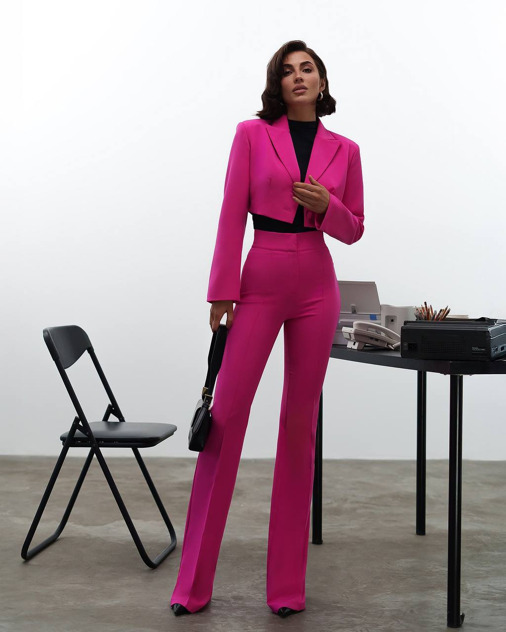 Woman in a bright pink suit standing in an office setting.