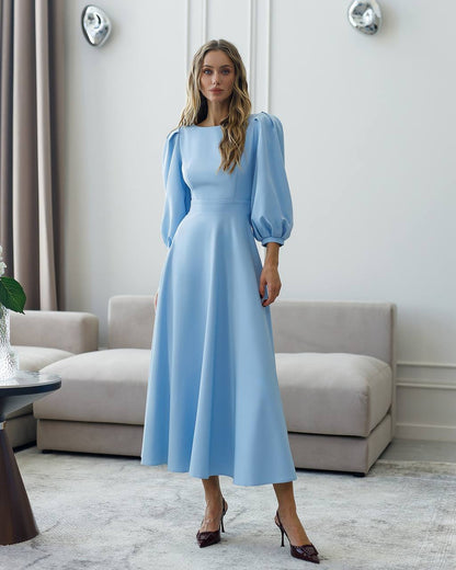 Woman wearing a light blue dress in a modern living room.
