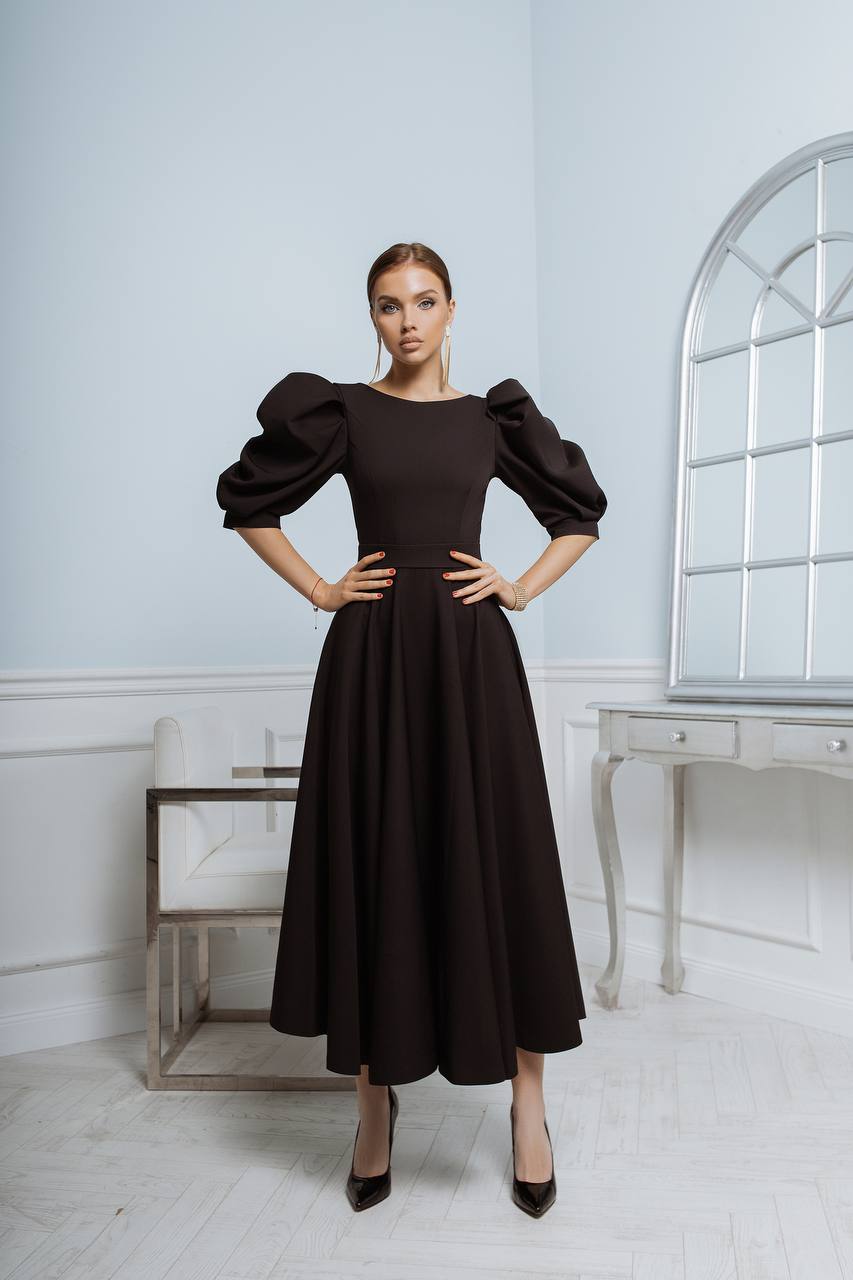 Woman wearing a black dress with puffed sleeves in an elegant room.