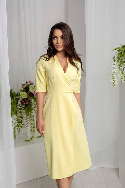Woman wearing a yellow dress standing in a room with white curtains and floral decorations.