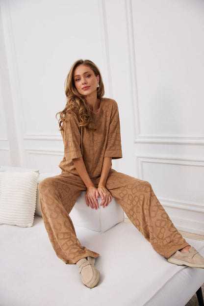 Woman in a brown outfit sitting on a white couch with a white wall background