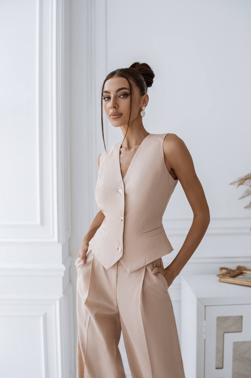 Woman wearing a beige suit standing against a white wall